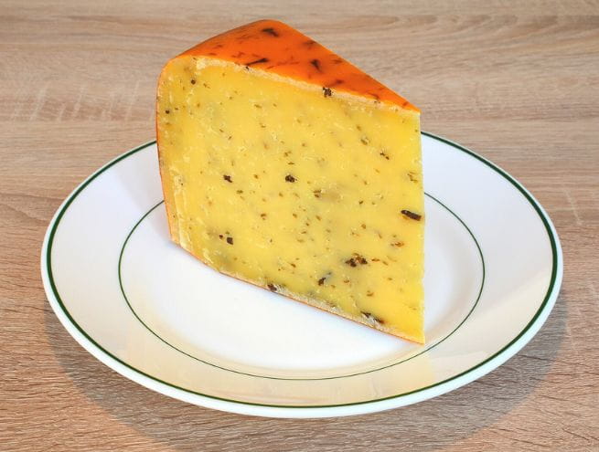 Herbed cheese with a golden rind, served on a white plate with green trim