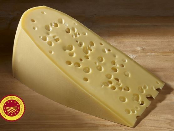 Morceau de fromage à pâte dure avec trous, posé sur une surface en bois.
