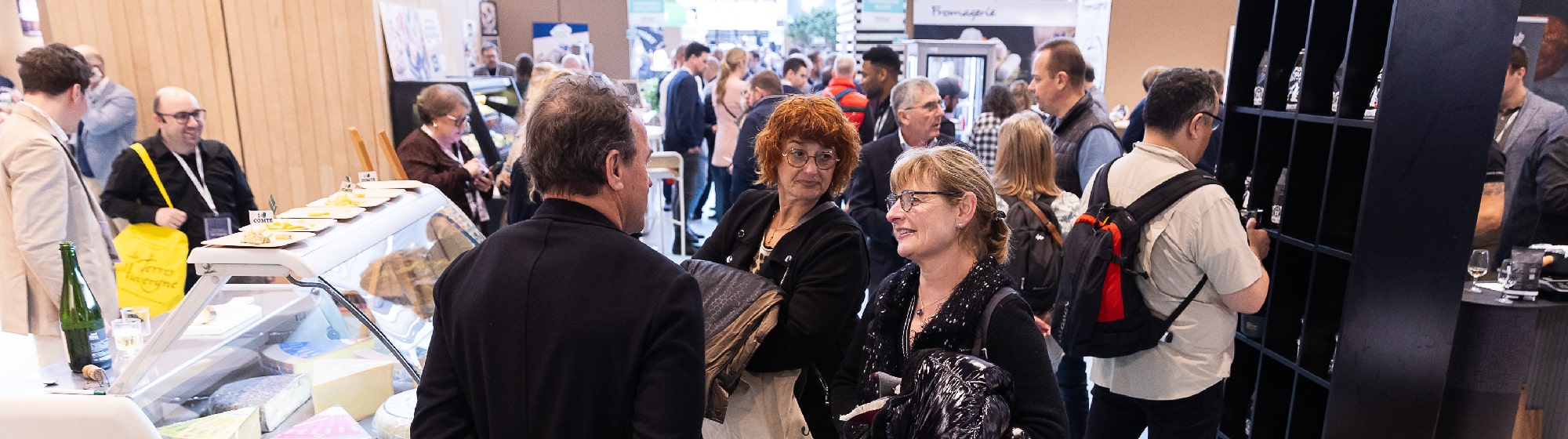 Des visiteurs autour d'un stand de fromages. 