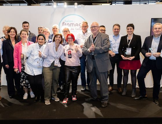 Groupe de personnes lors du salon du fromage, avec des trophées du concours coups de cœur 2024, tenant des prix à la main.